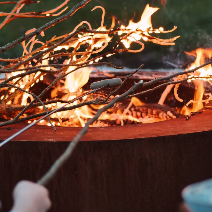 Grillen über der runden Cortenstahl Feuerstelle