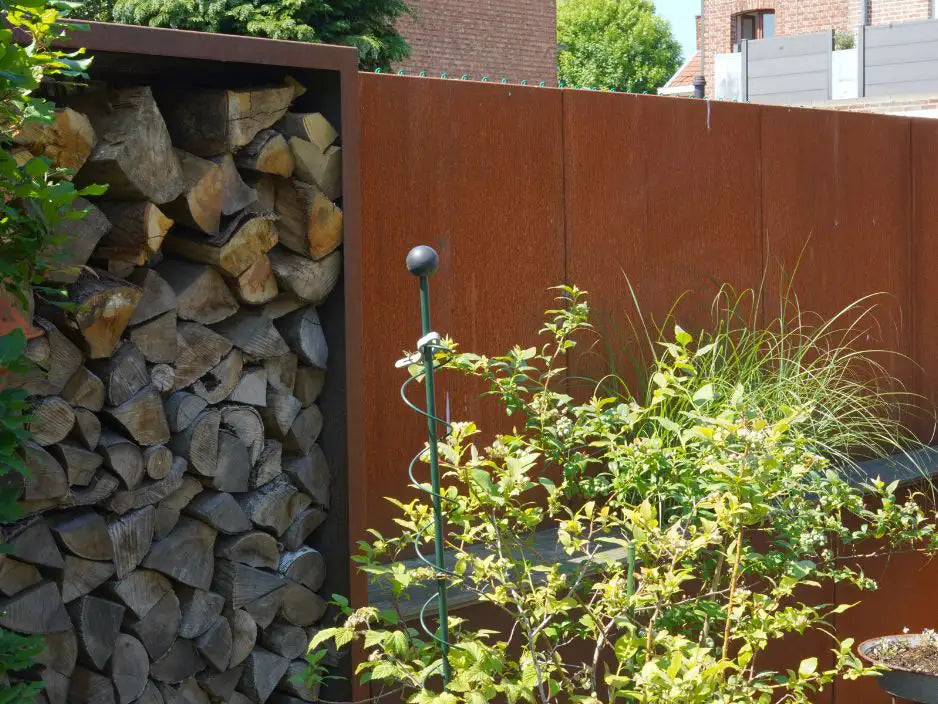 Cortenstahl Holzlager mit einer grünen Pflanze und Gartendeko im Vordergrund