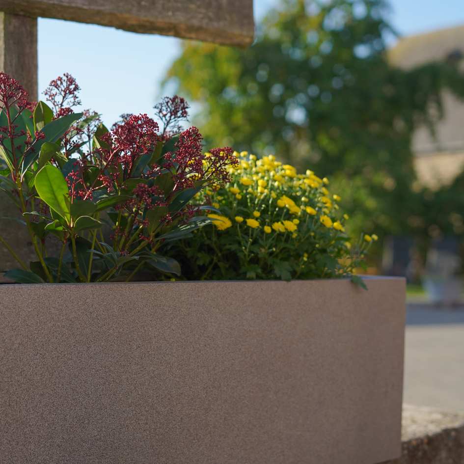 Nahaufnahme eines Fiberglas Pflanzkübels mit roten und gelben Blumen darin