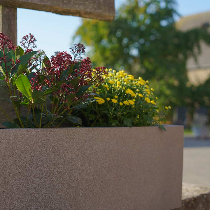 Nahaufnahme eines Fiberglas Pflanzkübels mit roten und gelben Blumen darin