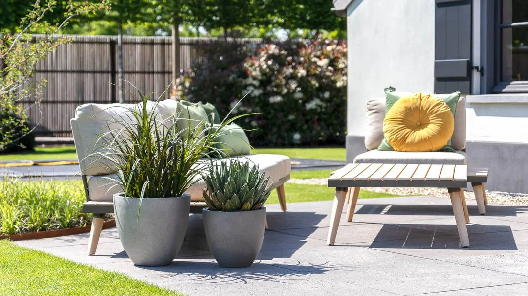 Betonoptik Pflanzkübel in einem modernden Garten neben einer Liege aus Holz