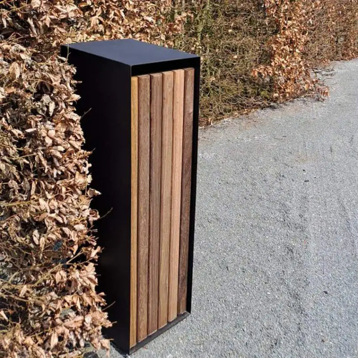 Standbriefkasten aus Stahl mit Holzverkleidung vor einer Hecke im Herbst